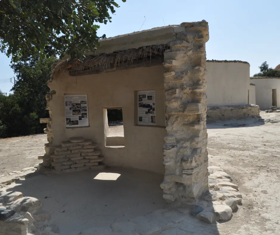 A cut-away reconstruction of a dwelling showing its thatch and mud roof in section, with two display panels mounted on the wall