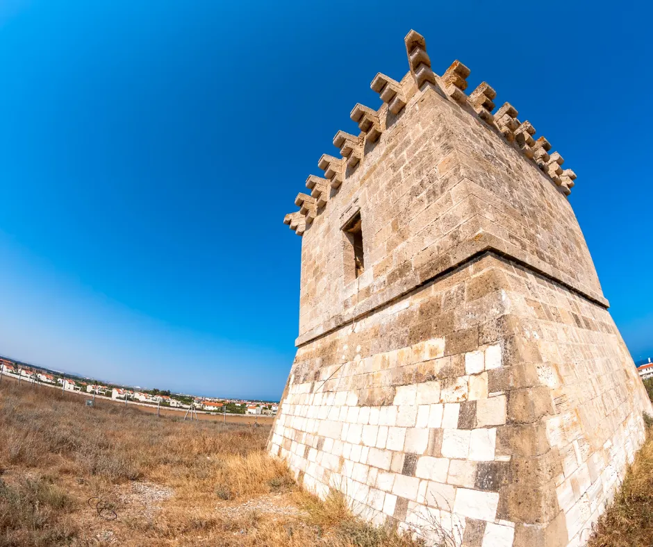 Kiti Tower seen from below at one corner — the sloping stone base, the doorway set high in the wall and the row of corbels carrying the parapet