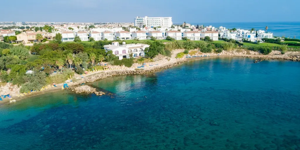 Sirena Bay in Protaras, with clear water, a sandy shoreline and low rocks