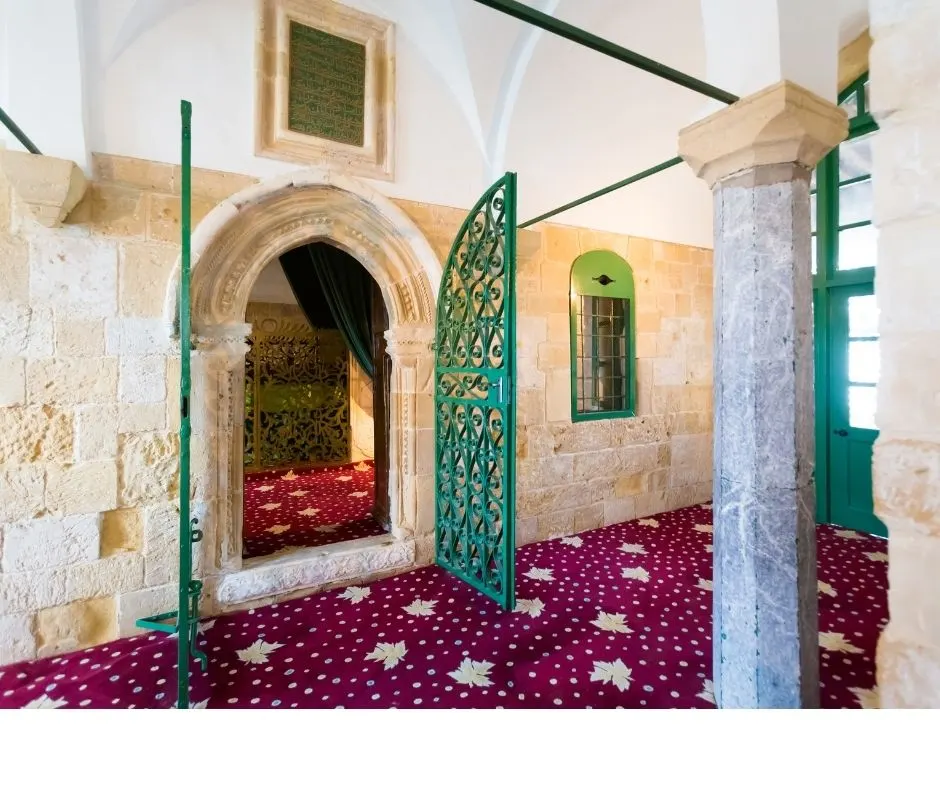 Inside Hala Sultan Tekke — an arched doorway, stone columns and a deep red patterned carpet